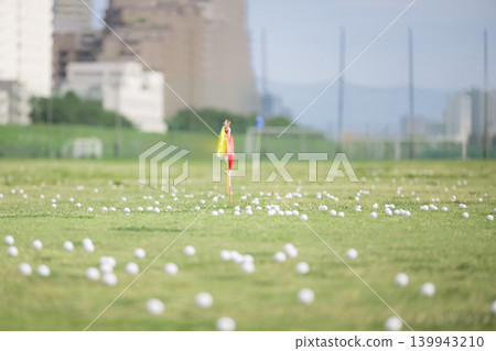 A sports background image of golf balls and flags lined up at a driving range; an image of an empty driving range. A sports background image of golf balls and flags lined up at a driving range; an image of an empty driving range. 139943210