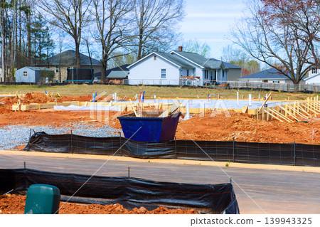 Construction is in progress at site with foundation work taking place materials set up in neighborhood. Construction is in progress at site with foundation work taking place materials set up in neighborhood. 139943325