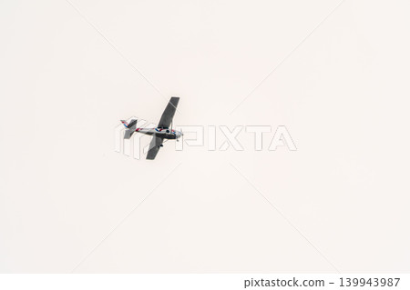 Small ultralight airplane with overhead wing and single propeller flying in sunset sky. 139943987