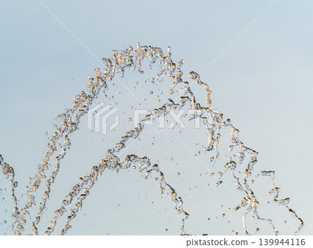 Splashes and jets of water against light background. Splashes and jets of water against light background. 139944116