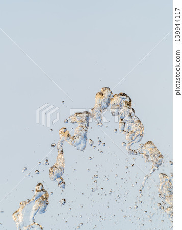 Splashes and jets of water against light background. Splashes and jets of water against light background. 139944117