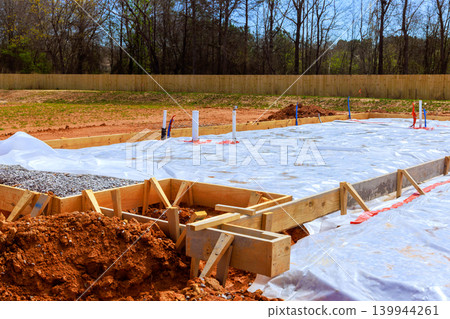 Construction workers prepare foundation by setting wooden forms laying plastic sheeting 139944261