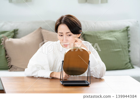 一個女人在鏡子裡檢查她的皮膚 一個女人在鏡子裡檢查她的皮膚 139944384