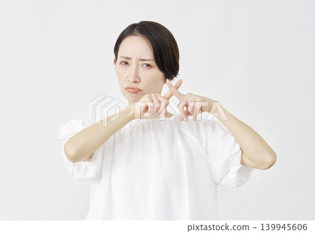 一位中年婦女在白色背景前擺出「X」形姿勢。 139945606