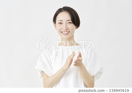一位中年婦女在白色背景前鼓掌。 139945619