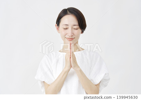 A middle-aged woman praying against a white background. A middle-aged woman praying against a white background. 139945630