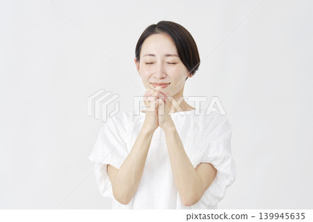 A middle-aged woman praying against a white background. A middle-aged woman praying against a white background. 139945635