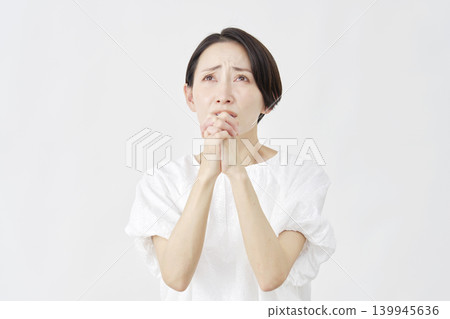 一位中年婦女在白色背景前懇求。 139945636