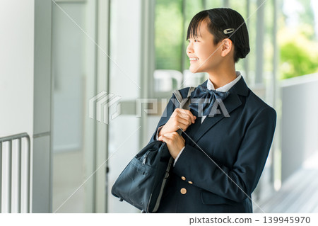 Junior high and high school girls in uniform walking in a school hallway 139945970