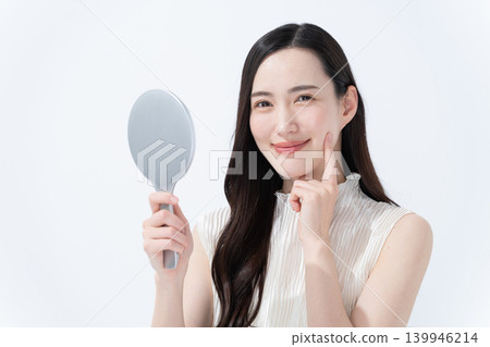一位女士對著手鏡檢查自己的皮膚。 139946214