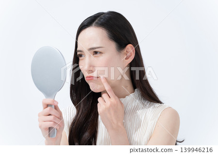 A woman checks her skin in a hand mirror. A woman checks her skin in a hand mirror. 139946216