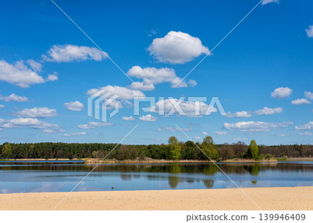 Calm lake with sandy beach under blue sky Calm lake with sandy beach under blue sky 139946409