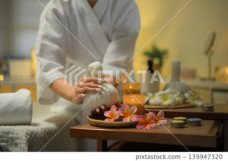 Spa setup with herbal compress candles flowers and relaxing wellness mood 139947320