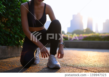 Cropped shot fitness, woman tying shoe for running preparation, workout or training exercise with water bottle 139947323