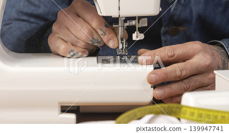 Person's hands threading a modern sewing machine needle Person's hands threading a modern sewing machine needle 139947741