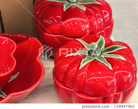 Red ceramic tomato shaped lidded containers and bowl on wooden table Red ceramic tomato shaped lidded containers and bowl on wooden table 139947902