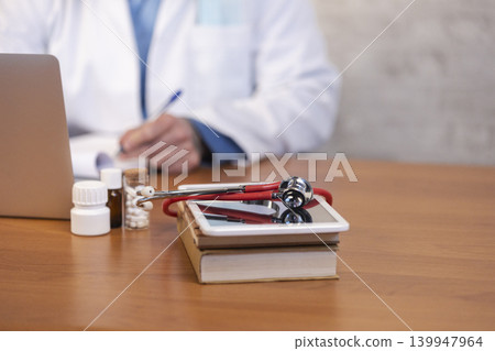 Doctor writing prescription with medical equipment beside Doctor writing prescription with medical equipment beside 139947964