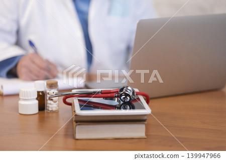 Doctor writing prescription, using laptop for telehealth Doctor writing prescription, using laptop for telehealth 139947966