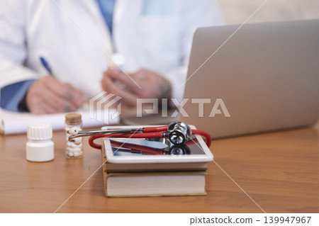 Doctor writing prescription, holding bottle of medicine Doctor writing prescription, holding bottle of medicine 139947967