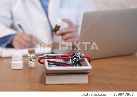 Doctor writing prescription, using laptop and medical tools Doctor writing prescription, using laptop and medical tools 139947968