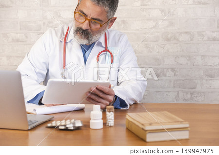 Doctor using tablet for telemedicine consultation in clinic 139947975
