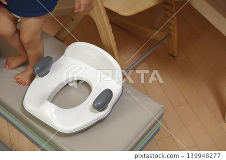 A child undergoing toilet training at home and a toilet seat reducer. A child undergoing toilet training at home and a toilet seat reducer. 139948277
