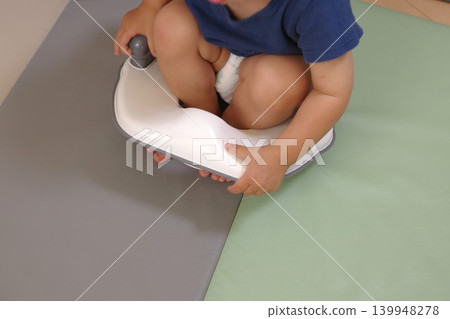 一個孩子坐在兒童馬桶座圈上。 一個孩子坐在兒童馬桶座圈上。 139948278