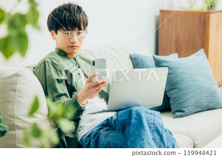 一個在客廳裡使用智能手機的人 一個在客廳裡使用智能手機的人 139948421