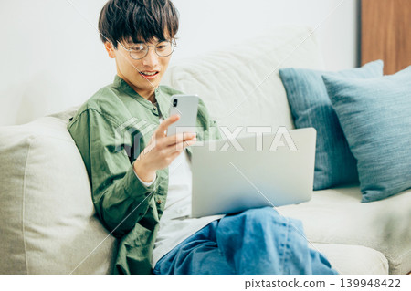一個在客廳裡使用智能手機的人 139948422