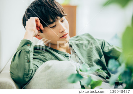 A man deep in thought in the living room. A man deep in thought in the living room. 139948427