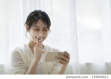 A smiling young woman looking at a smartphone screen A smiling young woman looking at a smartphone screen 139948821