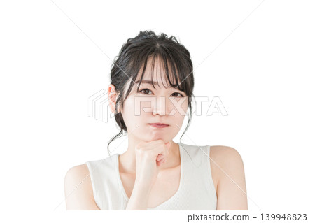 An Asian woman, resting her chin on her hand, ponders a problem (beauty, diet, spa treatments, hair removal). 139948823