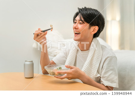 A young Asian man having a drink in his bedroom after taking a bath (beer, drinking at home, drinking habits) A young Asian man having a drink in his bedroom after taking a bath (beer, drinking at home, drinking habits) 139948944