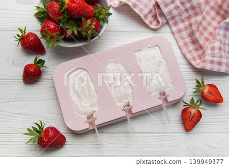 Preparing homemade strawberry yogurt popsicles on wooden table Preparing homemade strawberry yogurt popsicles on wooden table 139949377