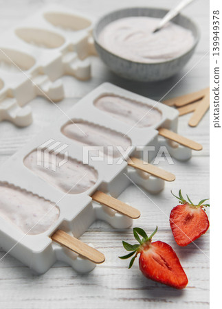 Preparing homemade strawberry popsicles in silicone molds Preparing homemade strawberry popsicles in silicone molds 139949378