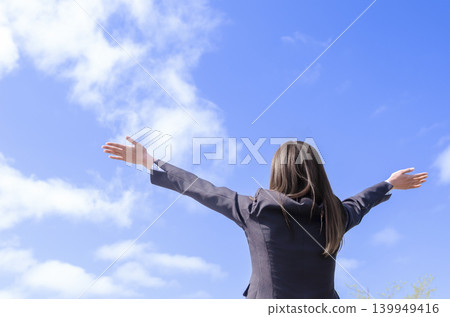 A back view of an office lady raising her arms in a victory pose (with an empty background). A back view of an office lady raising her arms in a victory pose (with an empty background). 139949416
