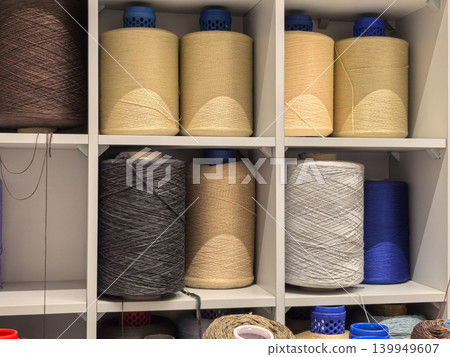 Industrial yarn cones in beige gray and blue on factory storage shelves Industrial yarn cones in beige gray and blue on factory storage shelves 139949607