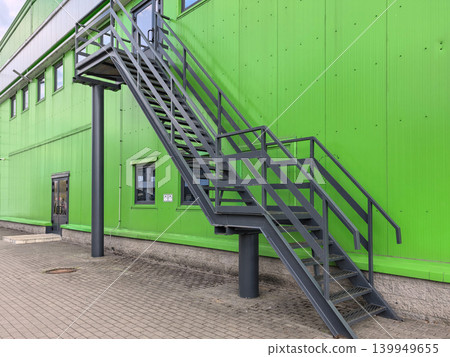 Outdoor metal staircase with platform on green warehouse building Outdoor metal staircase with platform on green warehouse building 139949655