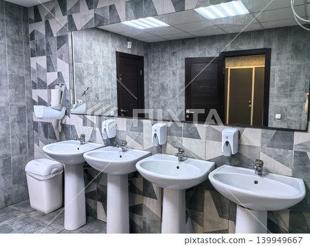 Public restroom interior with four white pedestal sinks and large mirror Public restroom interior with four white pedestal sinks and large mirror 139949667