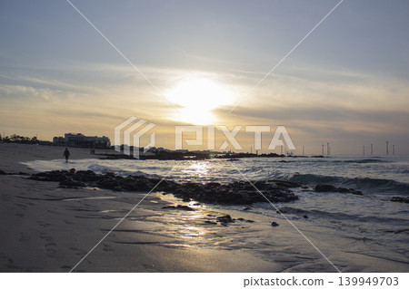 It is a beach scene with the sun setting. 139949703