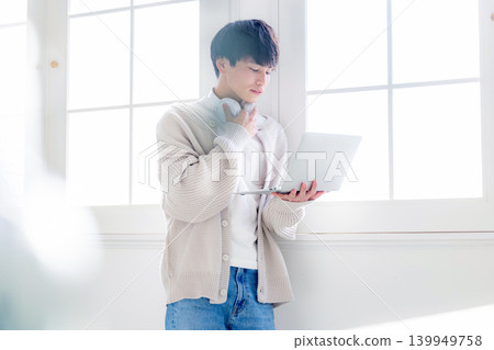 一個男人靠在窗邊看著電腦。 139949758