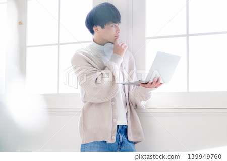 一個男人靠在窗邊看著電腦。 139949760