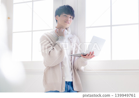 一個男人靠在窗邊看著電腦。 139949761