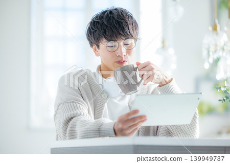 一名男子在窗邊操作平板電腦。 139949787
