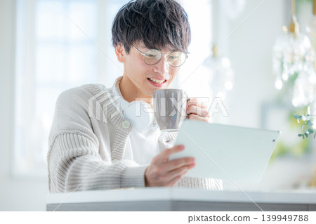一名男子在窗邊操作平板電腦。 139949788