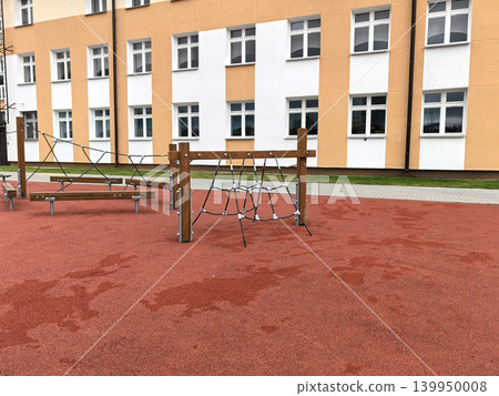 Modern wooden playground with climbing nets near school facade 139950008