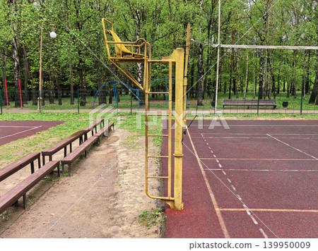 Empty outdoor volleyball court with yellow referee chair in green park 139950009