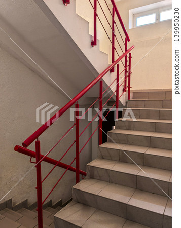 Bright red metal handrail on tiled staircase in modern building interior Bright red metal handrail on tiled staircase in modern building interior 139950230