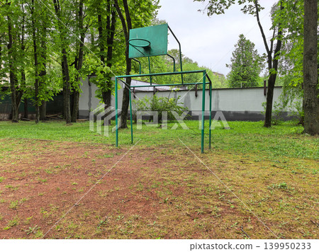 Old green basketball hoop and climbing frame in empty park yard Old green basketball hoop and climbing frame in empty park yard 139950233