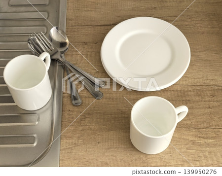 White plates mugs and stainless steel cutlery on wooden kitchen counter White plates mugs and stainless steel cutlery on wooden kitchen counter 139950276